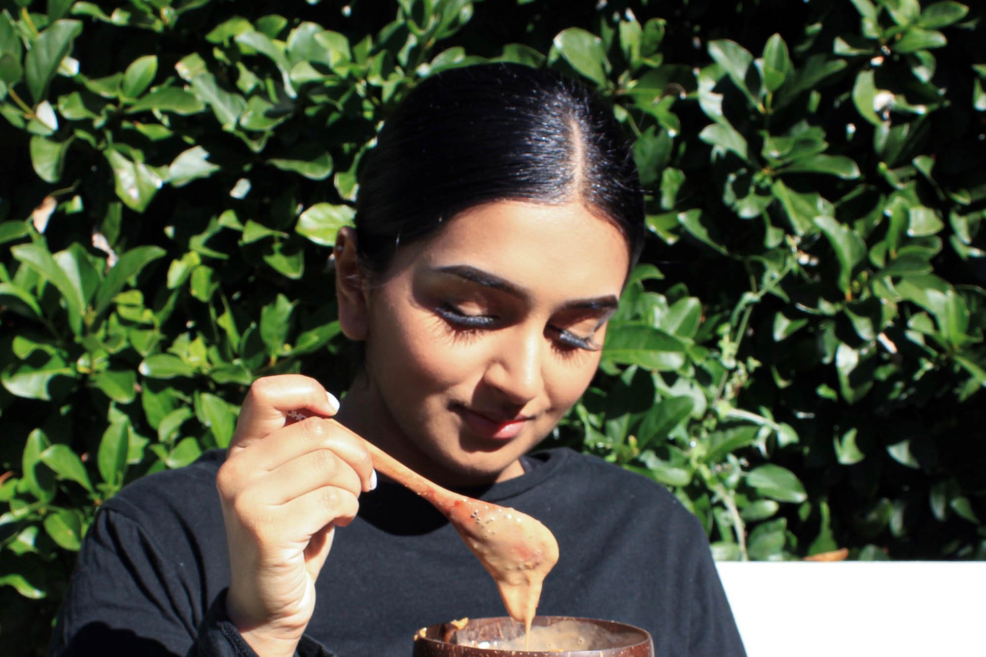 indian woman smiling at smoothie bowl